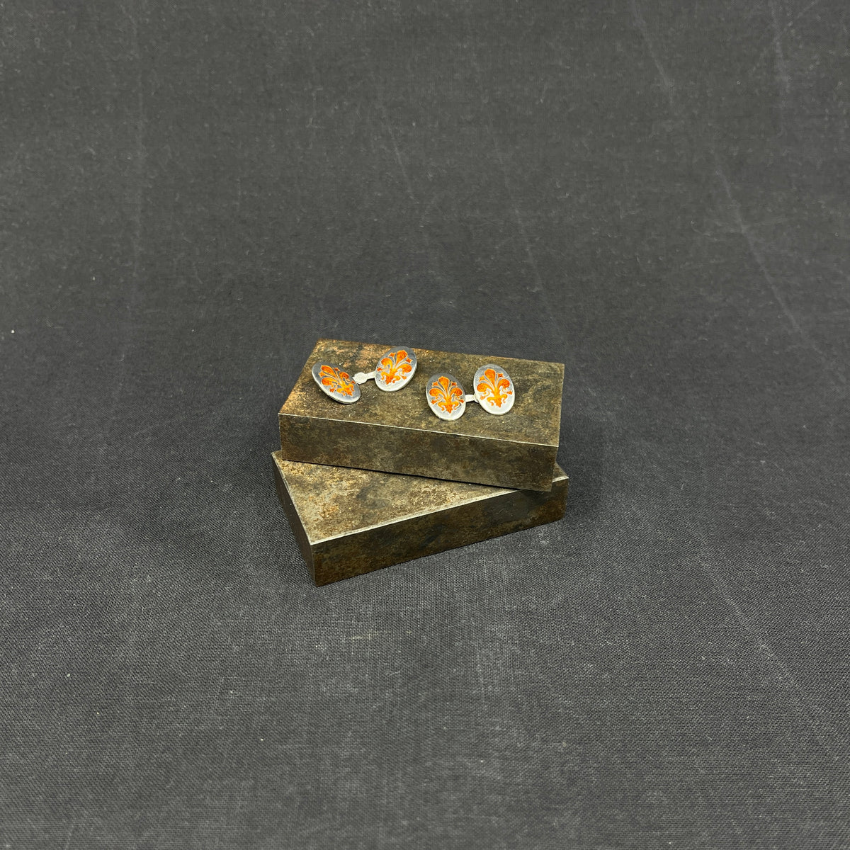 A pair of cufflinks with orange enamel