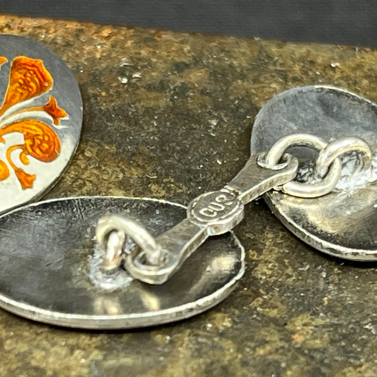 A pair of cufflinks with orange enamel
