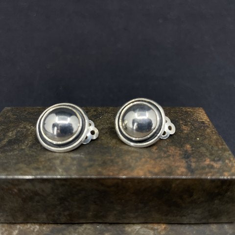 A pair of round ear clips in silver